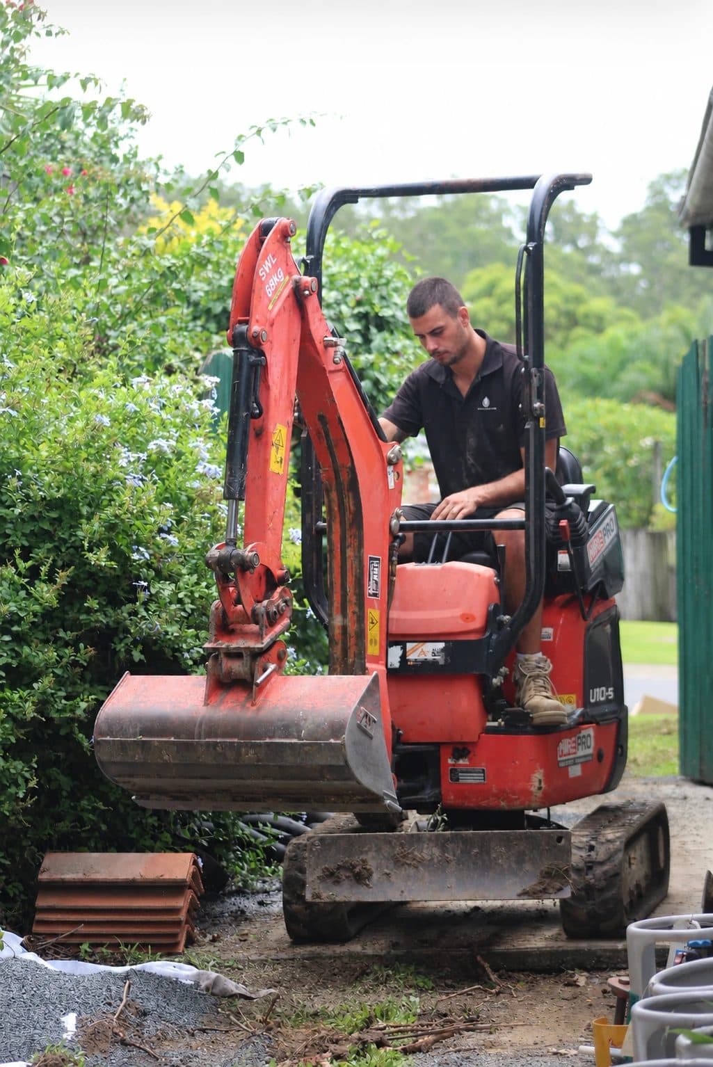 A Plumbtek Solutions team member operating a mini excavator on site